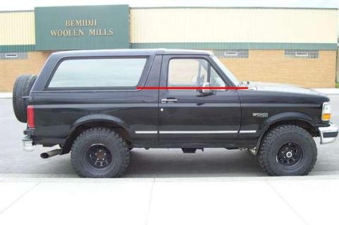 1996 Ford Bronco - Side profile of a black 1996 Ford Bronco parked in front of Bemidji Woolen Mills.