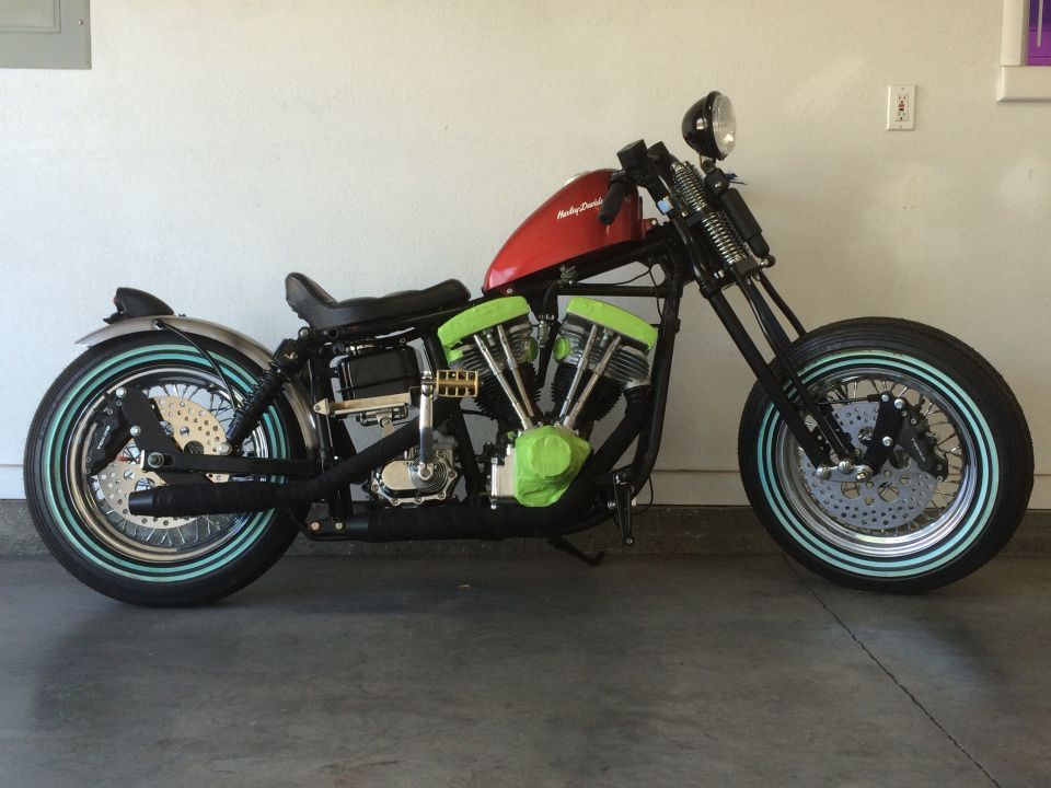 Custom motorcycle with red tank, green engine covers, and whitewall tires