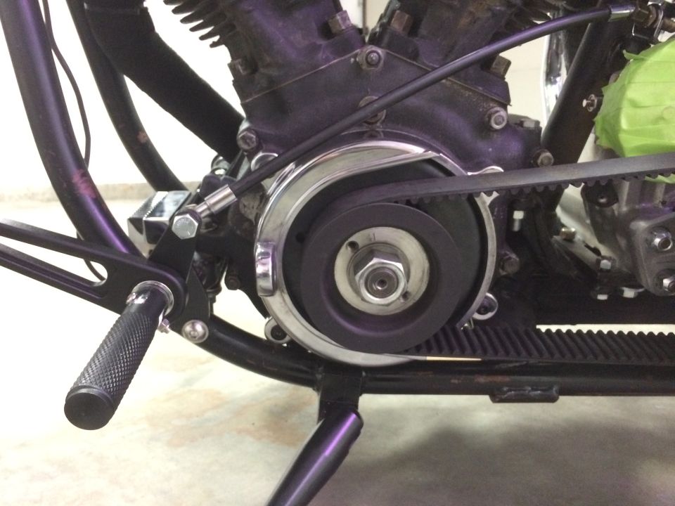 Motorcycle engine with belt drive system, black frame, and footpeg
