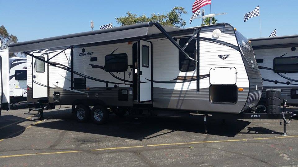 Travel trailer with awning extended, parked on asphalt lot