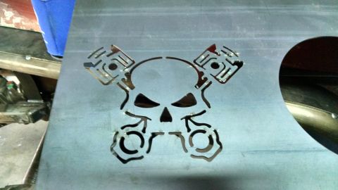 1985 Jeep CJ7 - A custom metal plate features a skull and piston design, likely for a vehicle modification.