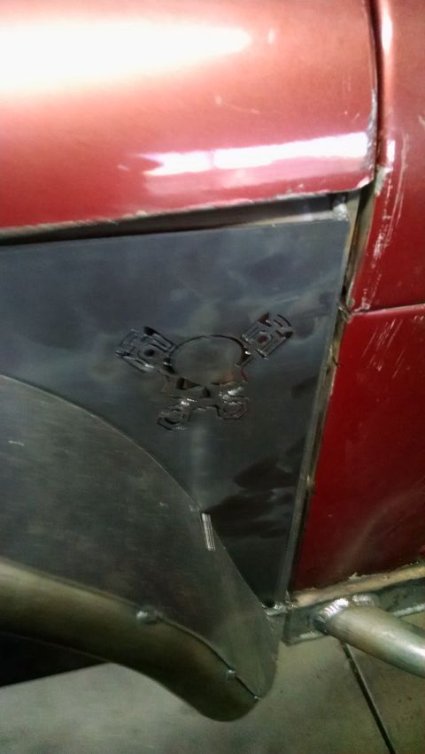 1985 Jeep CJ7 - A custom metal panel with a skull and piston design is attached to the fender of a red vehicle.
