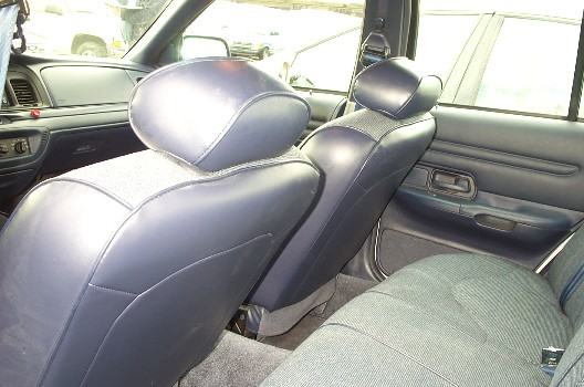 Rear-seat interior view of blue leather front seats and cloth rear bench in a Crown Victoria