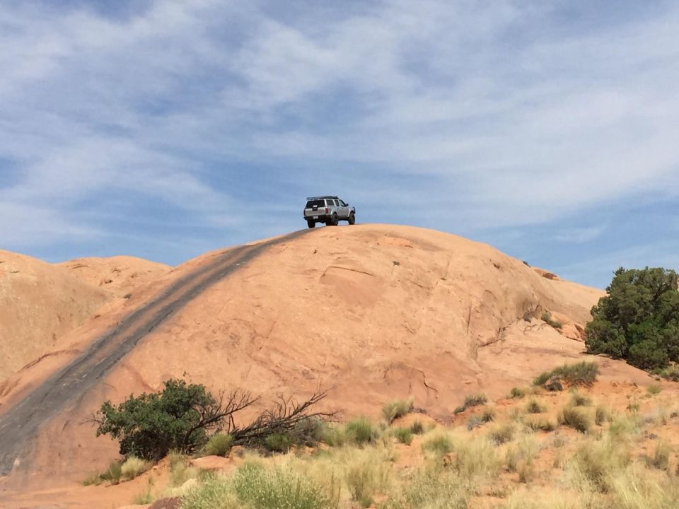Silver SUV on a rocky hill under a blue sky