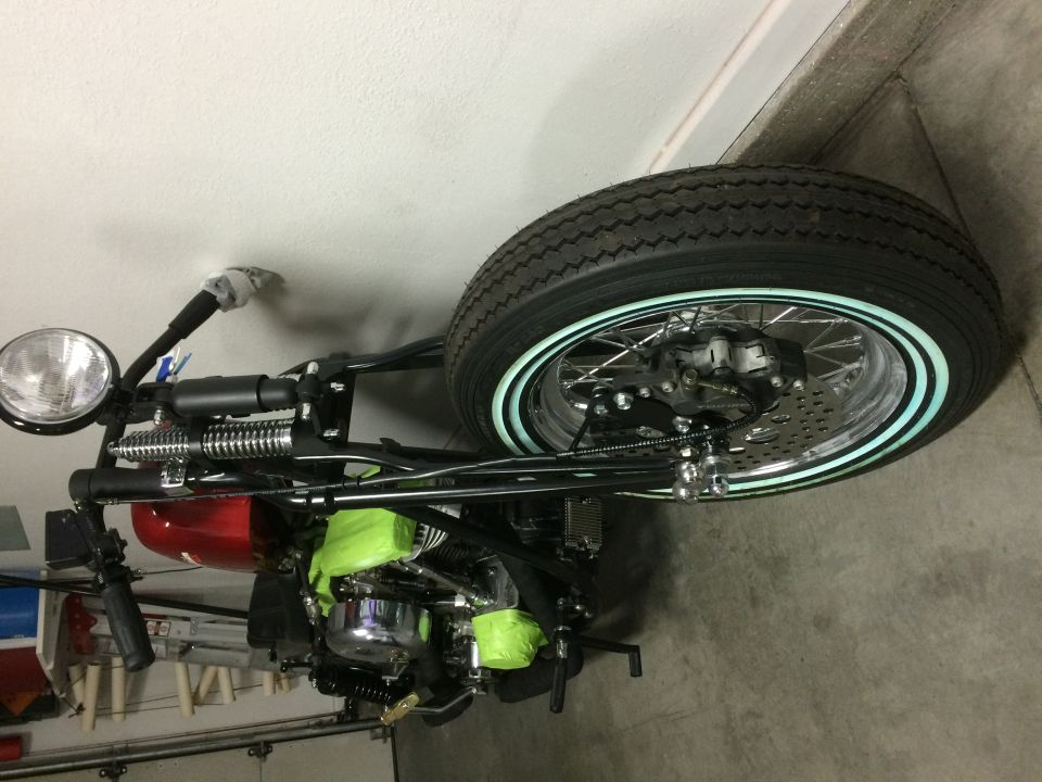 Motorcycle with a red gas tank and green engine covers, seen from the side