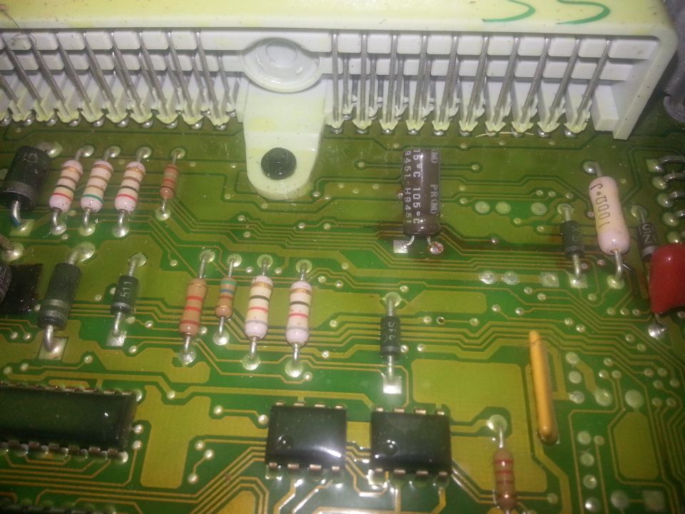 Close-up of a green circuit board with various electronic components and a white connector