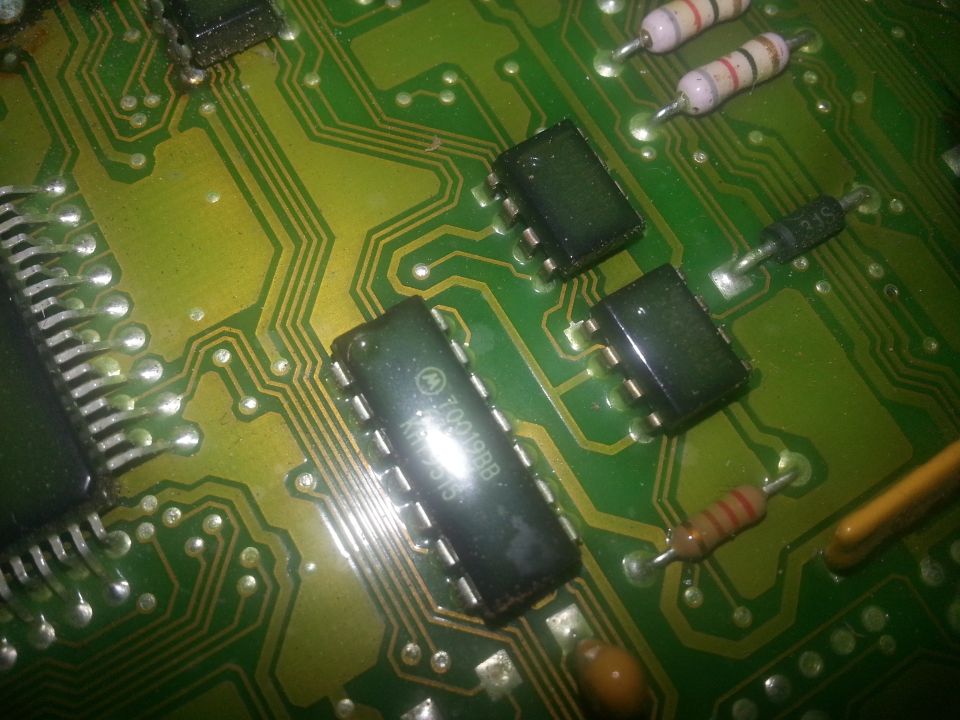 Close-up of a green circuit board with multiple integrated circuits, resistors, and diodes