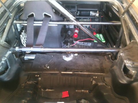 1991 Honda CRX - The interior of a modified vehicle features a roll cage, racing seat, fire extinguisher, and battery, suggesting a track-focused build.