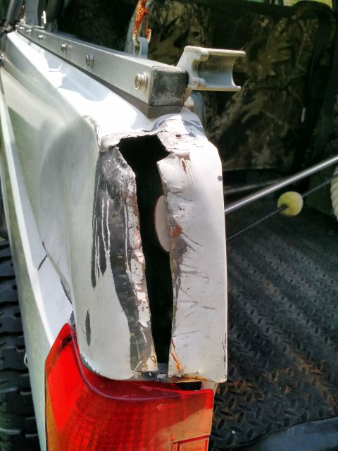 1992 Ford Bronco - The rear corner of a white truck bed shows significant damage with a gaping hole and rust.