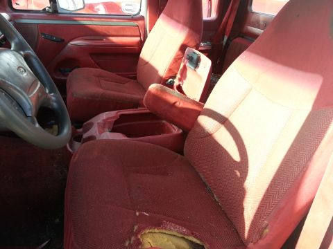 1994 Ford Bronco - Interior view of a truck with worn red upholstery and a damaged driver's seat.