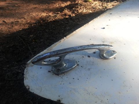 1973 Ford F-100 - A chrome door handle is visible on a white surface, with dirt scattered around it.