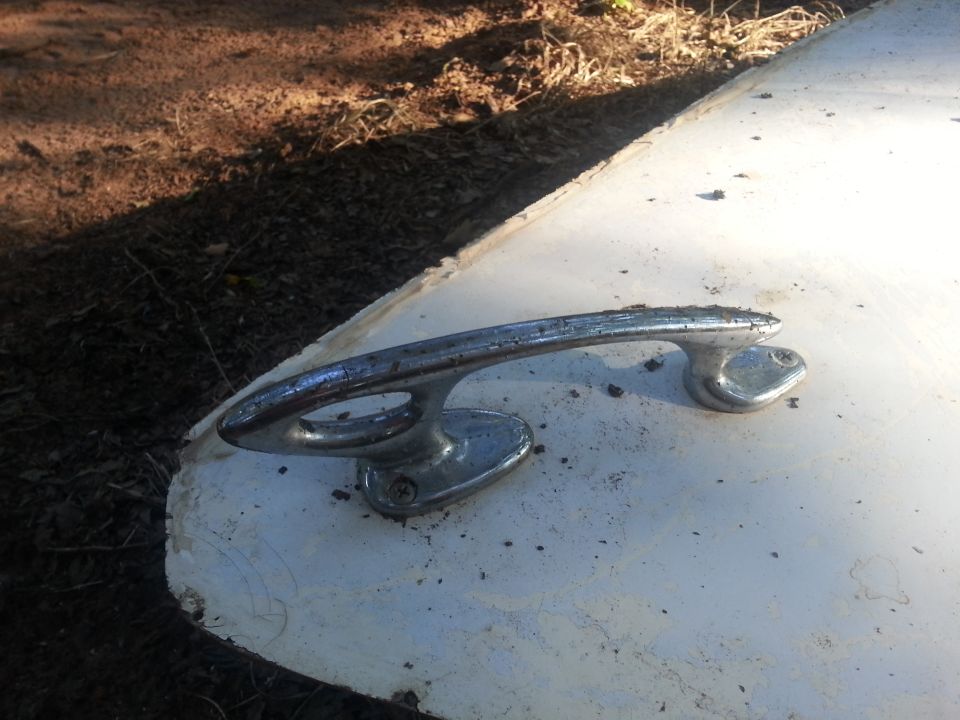 Chrome door handle on a white surface with dirt and debris