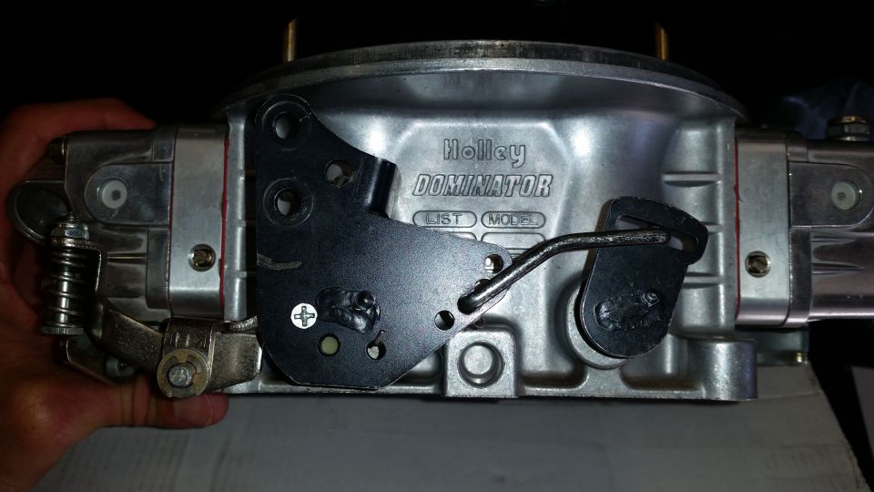 Holley Dominator carburetor with linkage and spring mechanism, held by a hand