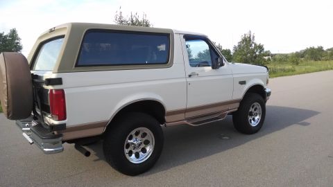 1994 Ford Bronco - This white Ford Bronco features a tan removable top and a spare tire mounted on the back.