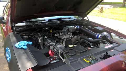 2004 Ford Crown Victoria - Engine bay of a 2004 Ford Crown Victoria, an aftermarket intake system and a Ford-branded fender cover.