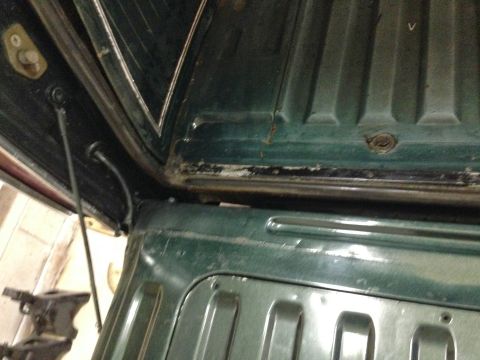 1979 Ford Bronco - Close-up of the interior of a dark green vehicle, focusing on the cargo area's ribbed metal and structural components.