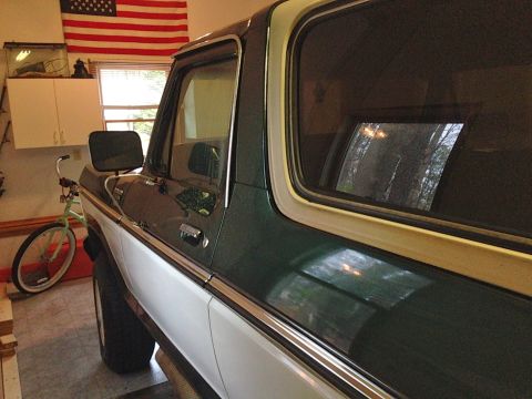 1979 Ford Bronco - The side profile of a classic Ford Bronco is visible, with a bicycle and an American flag in the background.
