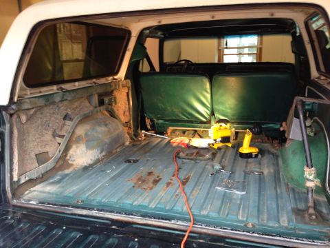 1979 Ford Bronco - The interior of a vehicle is shown with tools and some rust on the floor, suggesting ongoing work.