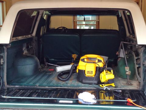 1979 Ford Bronco - Cleaning out the cargo area of a 1979 Ford Bronco, with a shop vac and other tools present.