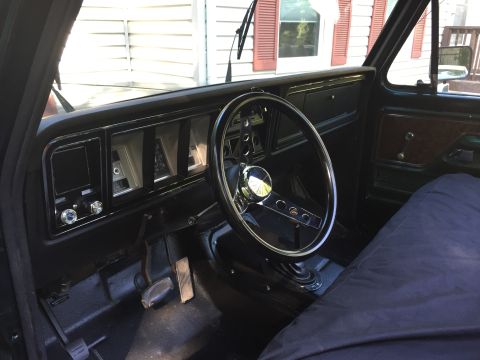 1979 Ford Bronco - The interior of a vintage truck shows the dashboard, steering wheel, and part of the passenger seat covered with a blue tarp.