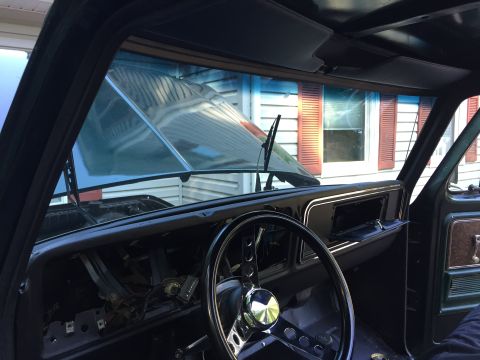 1979 Ford Bronco - The interior of a vehicle is shown with the hood open, revealing the dashboard and steering wheel.