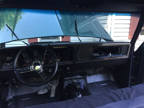 1979 Ford Bronco - The interior of a 1979 Ford Bronco shows a dashboard with an aftermarket steering wheel and missing radio components.
