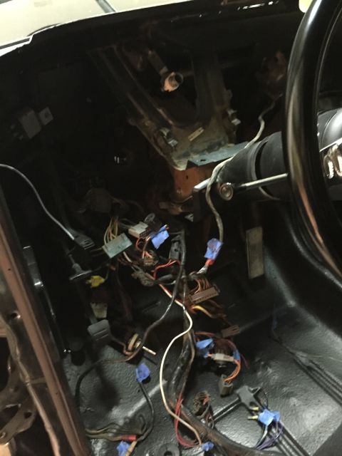 1979 Ford Bronco - The image shows the interior of a vehicle, focusing on the dashboard wiring harness. Various wires, connectors, and tape are visible, sugge…