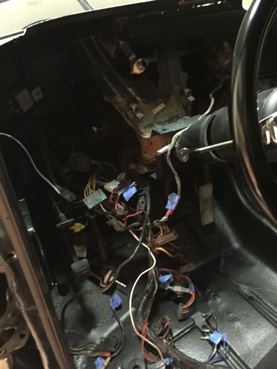 Close-up of a vehicle's dashboard wiring harness with many wires and connectors.