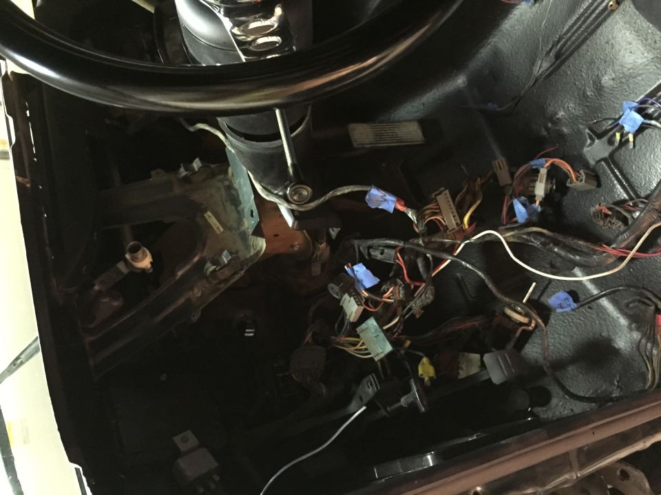 Close-up of vehicle wiring harness and steering column area.