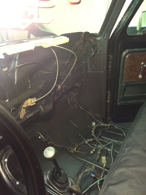 1979 Ford Bronco - The interior of a vintage vehicle is shown, focusing on the dashboard area and floor with exposed wiring and a manual transmission shifter.…
