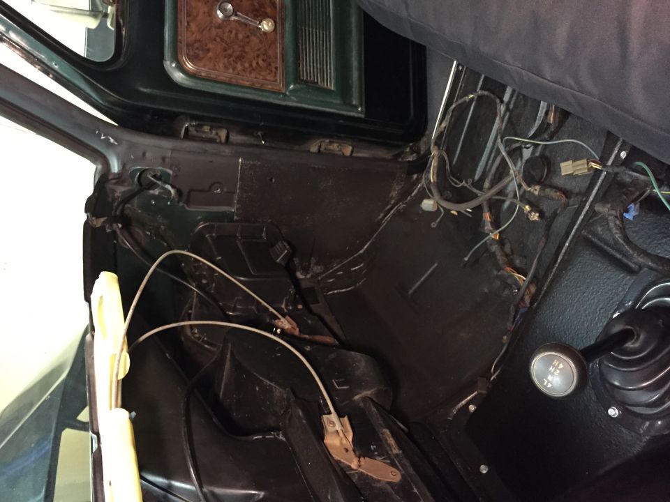 Interior of a vintage vehicle showing floor, wiring, shifter, and dashboard.