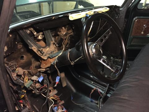 1979 Ford Bronco - The interior of a classic vehicle, likely a 1979 Ford Bronco, shows a disassembled dashboard with exposed wiring, pedals, and a steering wh…
