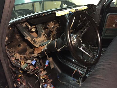 1979 Ford Bronco - The interior of a vehicle shows a disassembled dashboard with exposed wiring and a steering wheel. The steering column is also visible, alo…