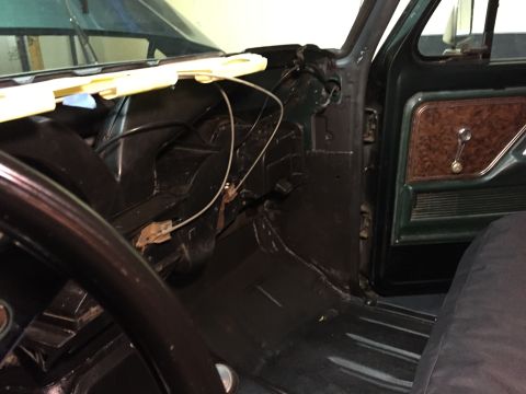 1979 Ford Bronco - Interior view of a dark green 1979 Ford Bronco, focusing on the driver's side dashboard area and door panel. The image shows the steering w…