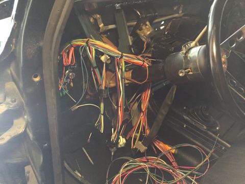 1979 Ford Bronco - The interior of a vehicle shows a complex wiring harness connected to the steering column and dashboard area. Various colored wires are bun…