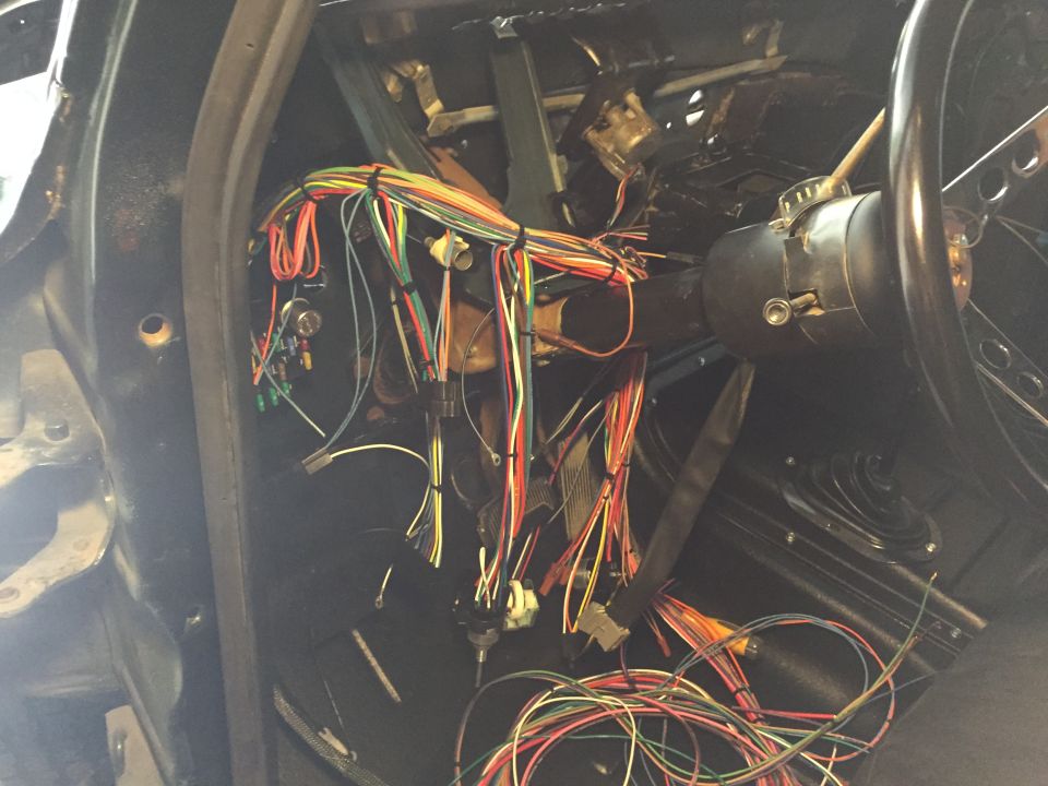 Vehicle interior with exposed wiring harness near steering column