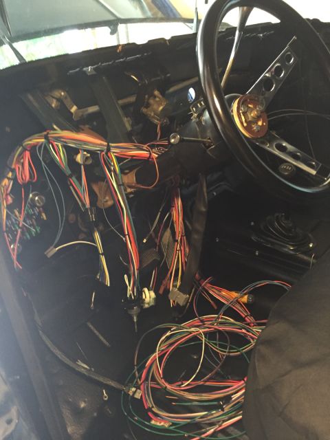 1979 Ford Bronco - The interior of a classic vehicle, likely a 1979 Ford Bronco, is shown with its dashboard disassembled and a complex wiring harness laid ou…