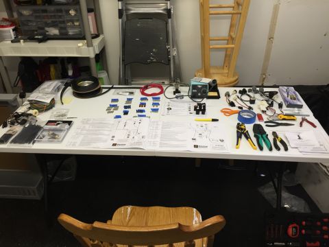 1979 Ford Bronco - A workbench is set up with various electrical components, wiring, tools, and diagrams, likely for a vehicle wiring project. The items inclu…