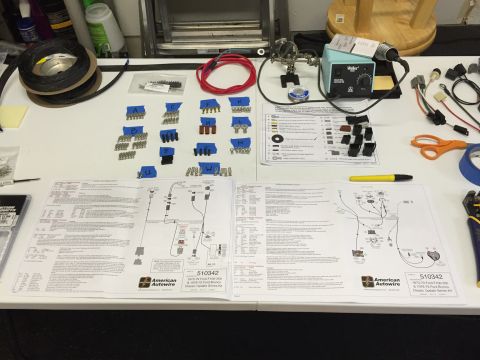 1979 Ford Bronco - A workbench is laid out with a vehicle wiring harness kit, including instructions, various connectors labeled with tape, a soldering iron,…