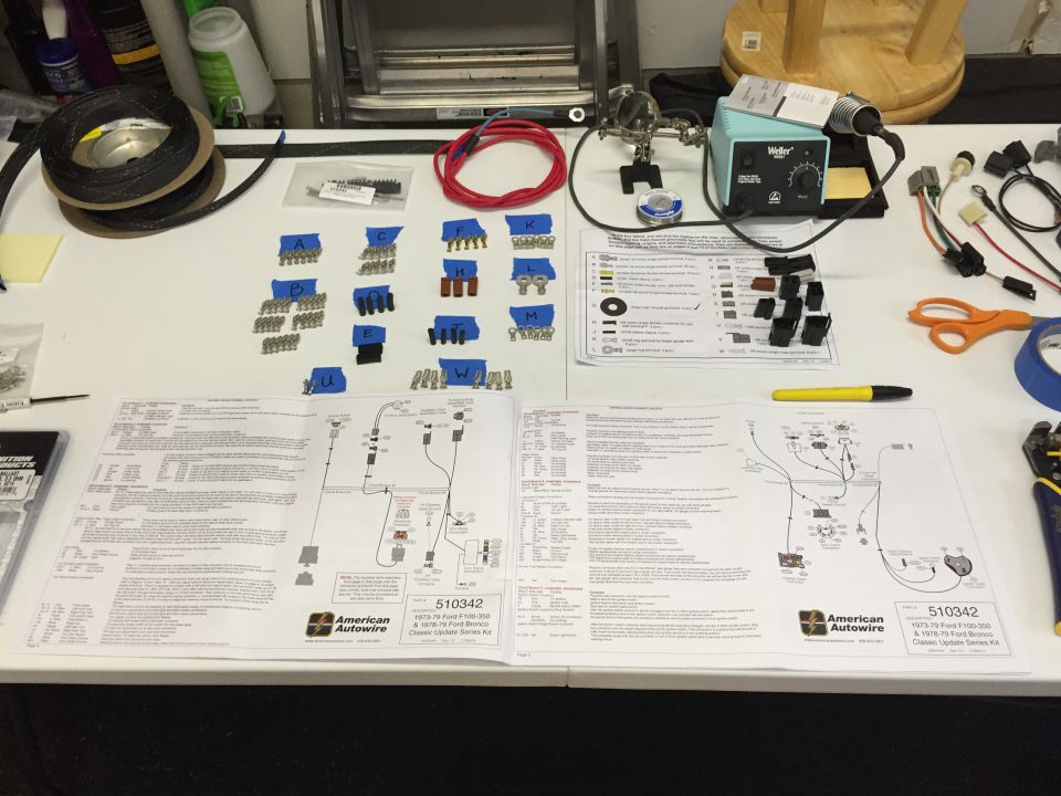 Vehicle wiring harness kit laid out on a workbench with instructions and tools.