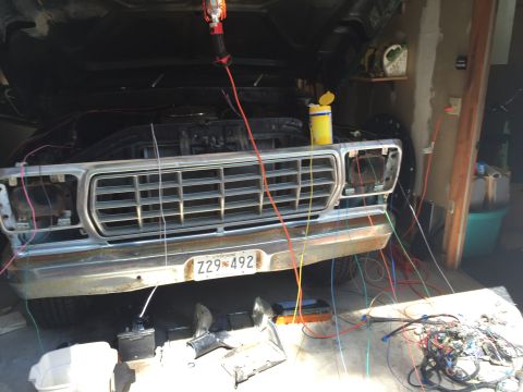 1979 Ford Bronco - A front view of a classic Ford truck or SUV with its hood open, undergoing electrical work. Numerous wires are disconnected and spread acro…
