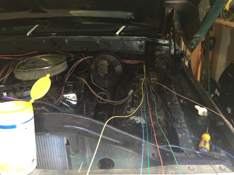 1979 Ford Bronco - The engine bay of a vintage Ford Bronco is shown with the hood open, revealing numerous colorful wires running across the engine and firewa…