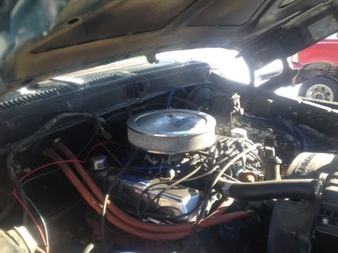 1979 Ford Bronco - The open hood of a vehicle reveals a close-up view of the engine bay, featuring a chrome air cleaner and various hoses and wires.