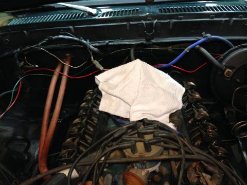 1979 Ford Bronco - The engine bay of a 1979 Ford Bronco is shown, with the V8 engine and various hoses, wires, and components visible. A white towel is placed…