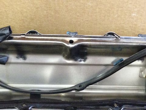 1979 Ford Bronco - Close-up view of the inside of a metal valve cover with a black rubber gasket attached. The metal has a brushed finish and shows some signs…
