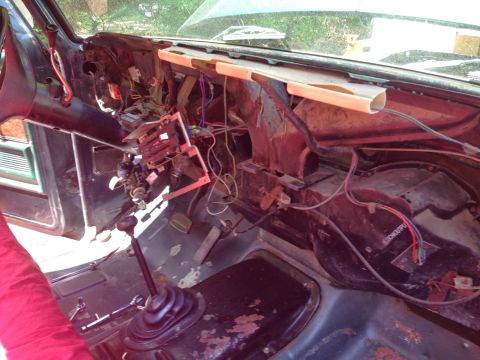 1979 Ford Bronco - The interior of a disassembled vehicle, likely a 1979 Ford Bronco, shows the dashboard area with exposed wiring, steering column, and floor…
