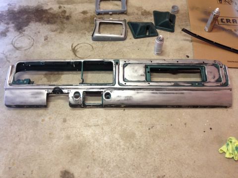 1979 Ford Bronco - A silver dashboard panel with cutouts for gauges and vents is laid out on a concrete floor. Several green plastic trim pieces and spray can…