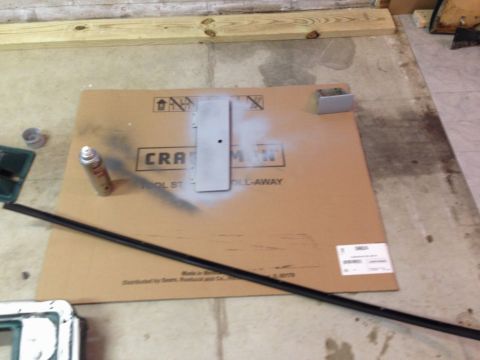 1979 Ford Bronco - A spray can is used to paint a metal part on a piece of cardboard, which is placed on a concrete floor. A black trim piece is laid across t…