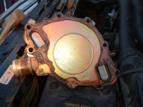 1987 Ford Bronco - A used water pump is shown with its gasket, sitting on top of engine components.