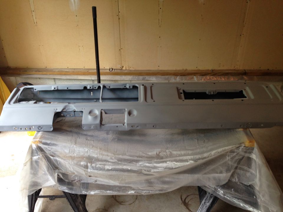 Gray primed vehicle dashboard assembly with instrument cutouts.